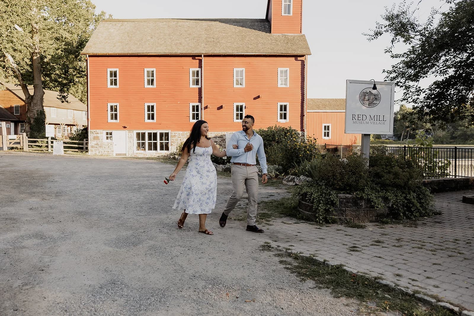 Anthony and Lily walking arm in arm past the Red Mill